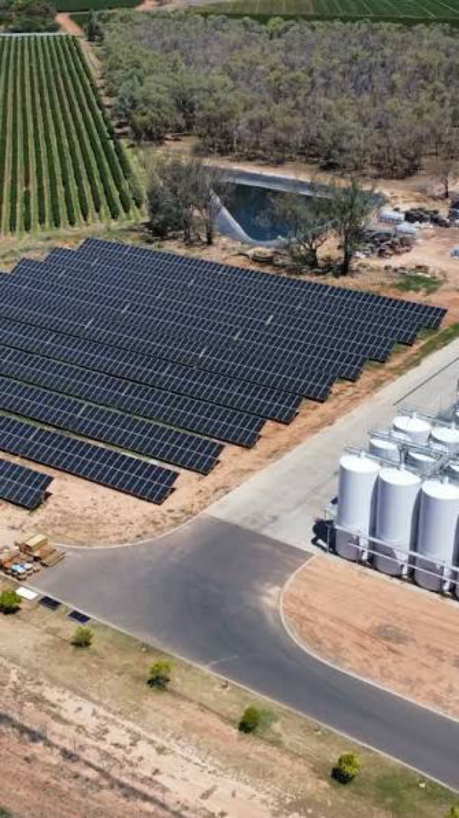 Large commercial ground-mount solar array next to agricultural storage tanks
